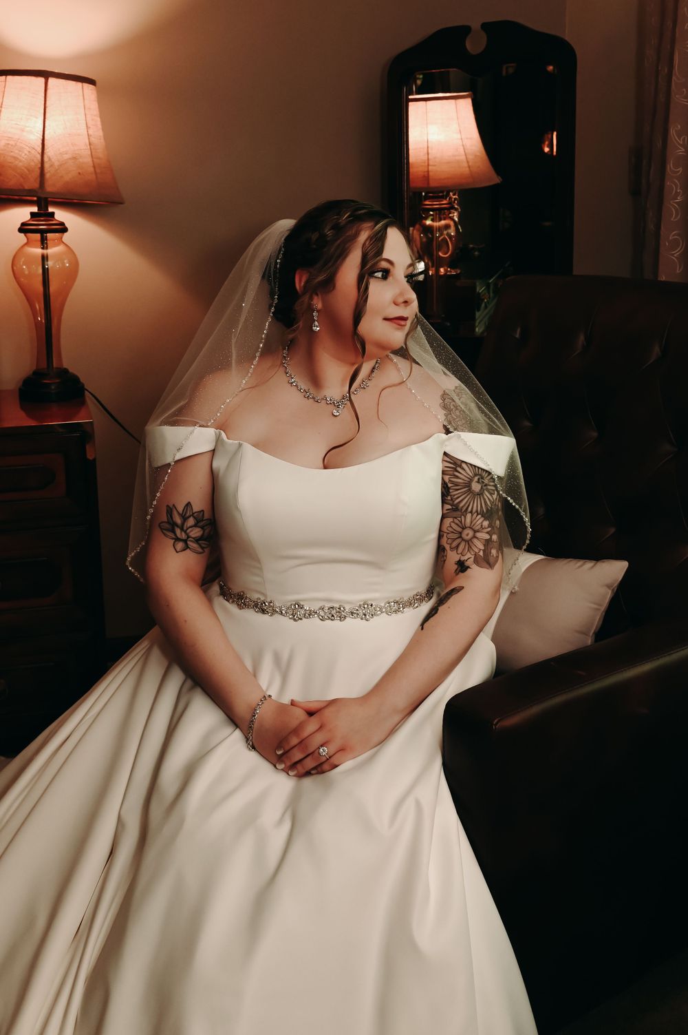 Classic white wedding dress with beaded belt detail photographed in warm ambient lighting.