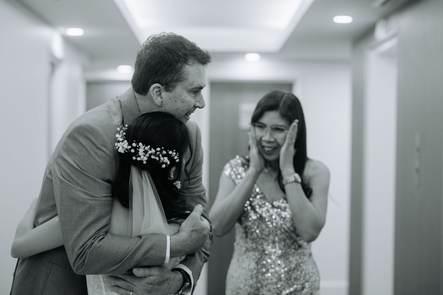 A black and white candid moment between two people in a hallway.