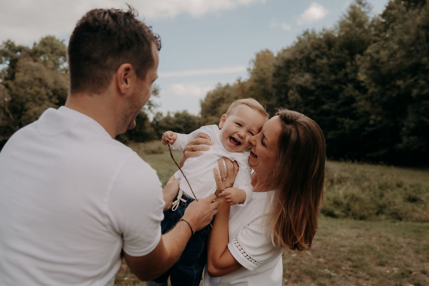 Joyful outdoor family photography session in natural setting during golden hour.