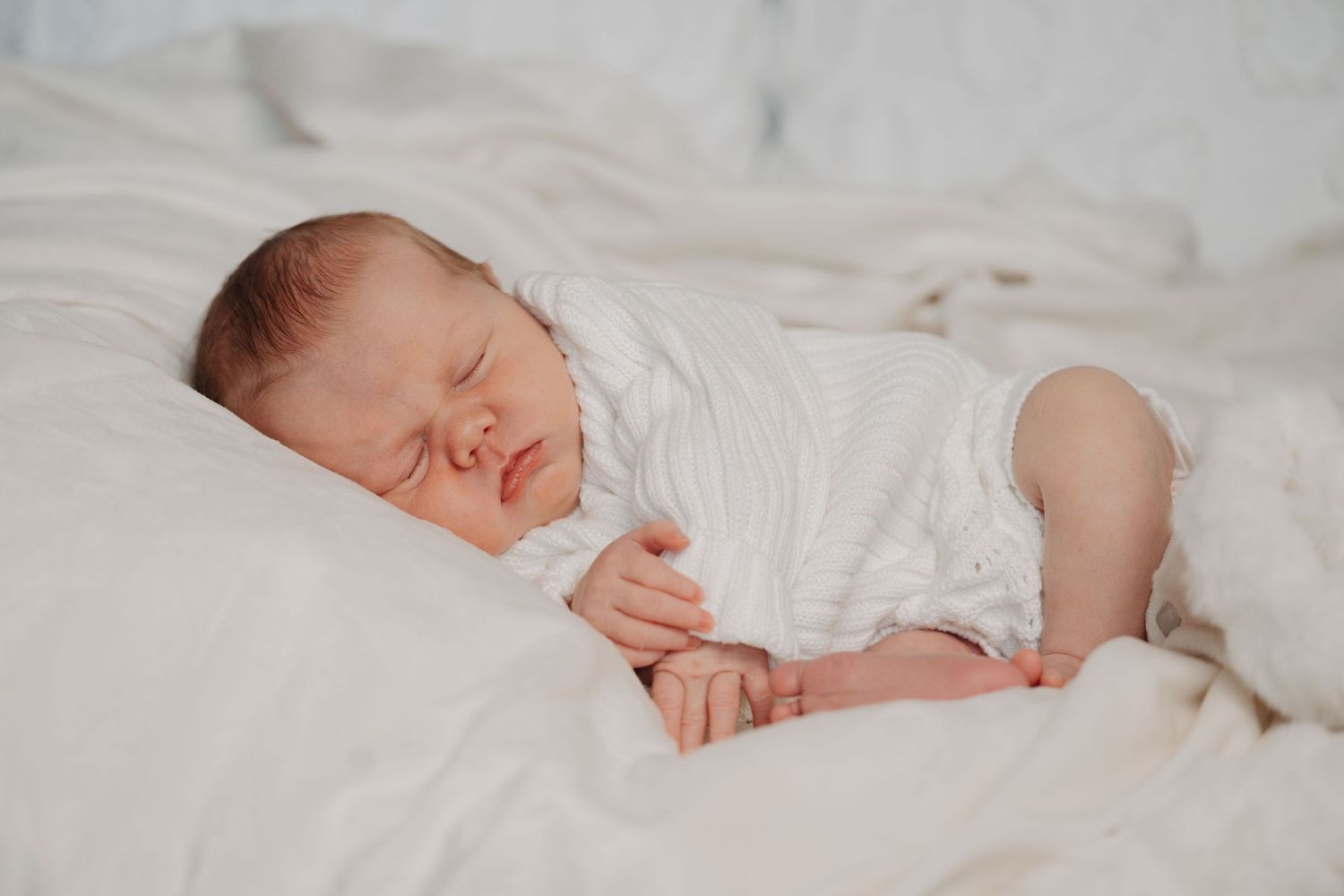 Intimate family moment as parents cuddle with newborn baby on couch in series of tender photos.
