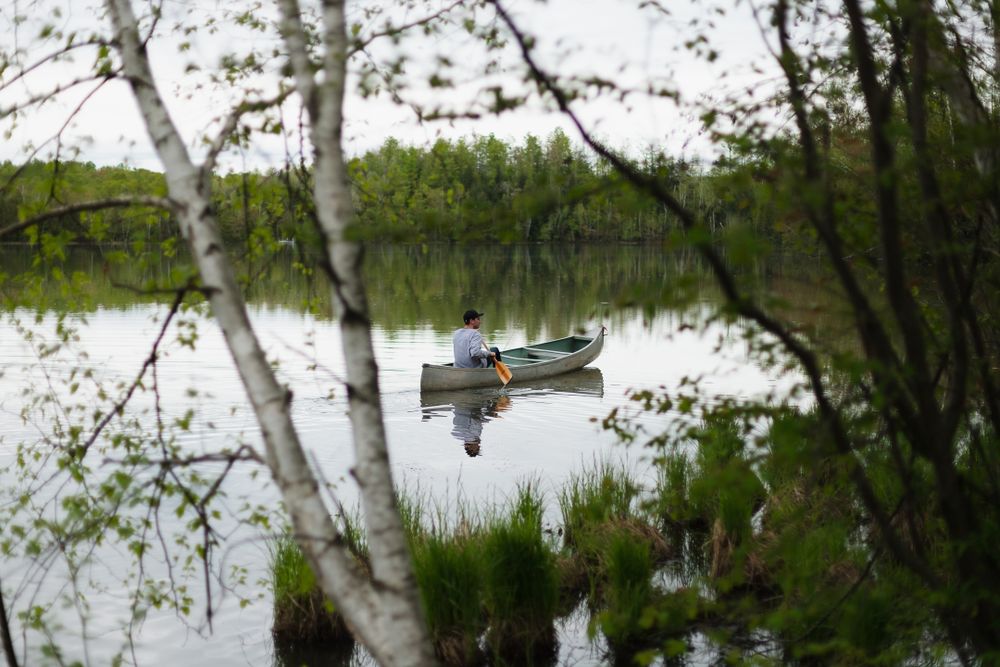 man canoeing on small lake in the woods