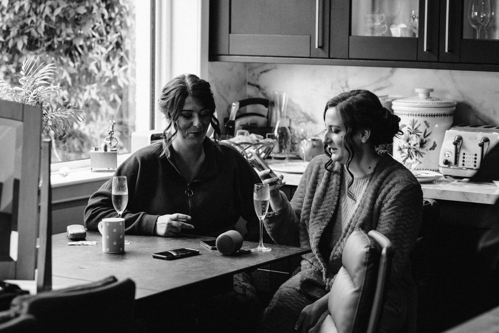 Black and white photo of people sharing a casual moment at a kitchen table.
