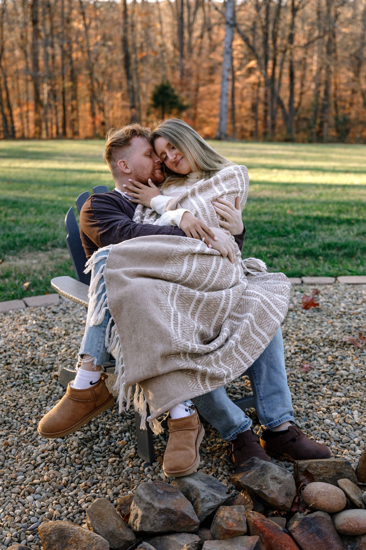 Autumn engagement photos on rustic rocks with cozy blanket wraps.