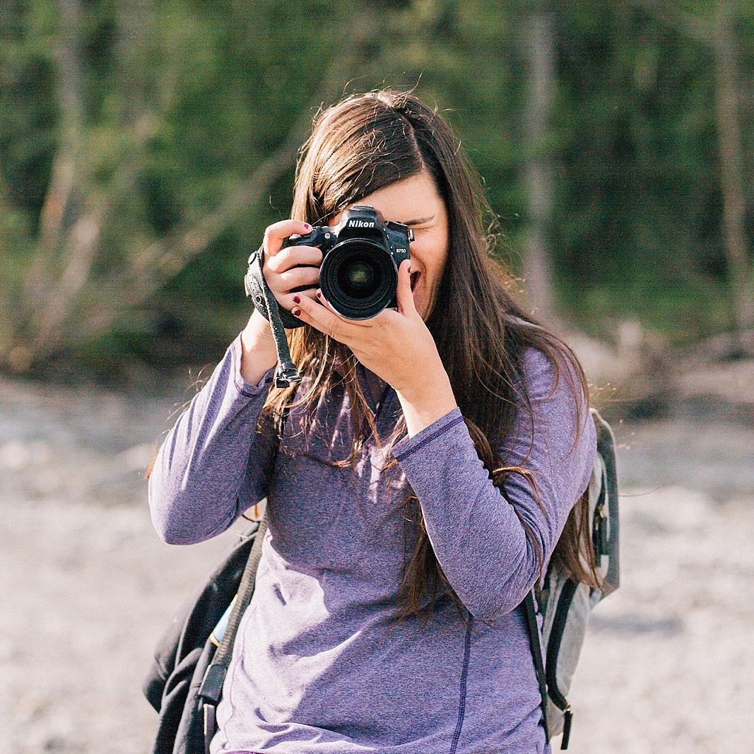 Photographer taking photos outdoors with a professional DSLR camera.