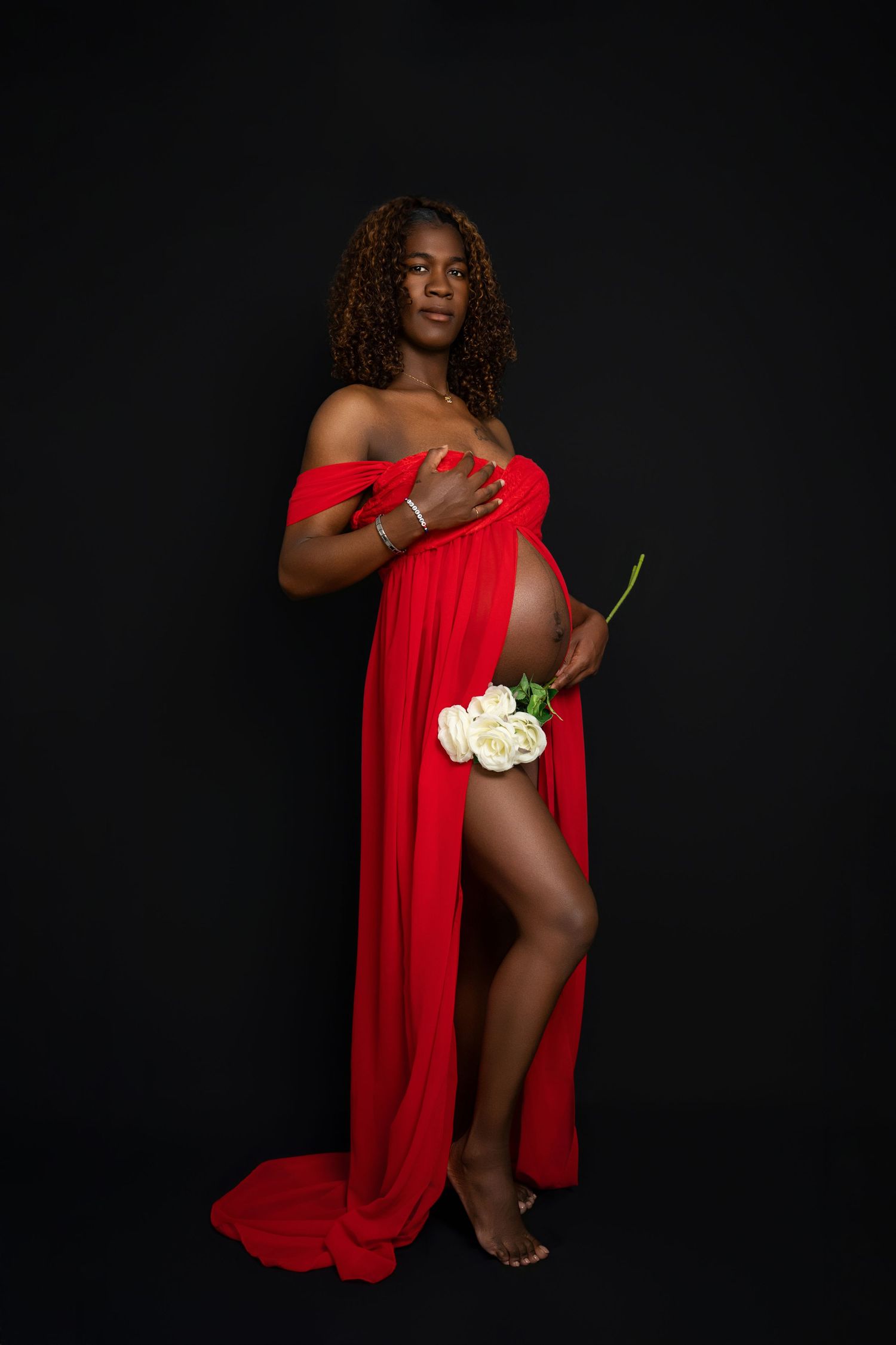 Artistic portrait with red fabric and white flowers against dark background.