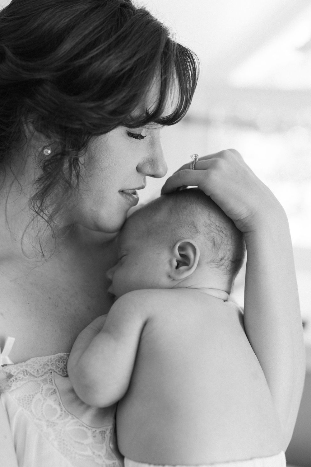 Black and white photo of a mother tenderly holding and kissing her newborn baby.