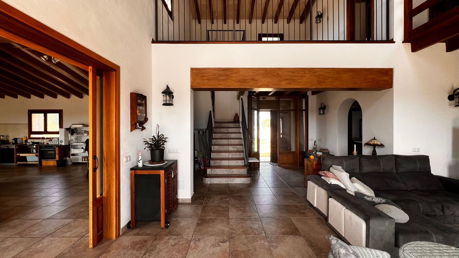 Spacious rustic villa interior featuring tiled floors, wooden beams, a staircase, and an open-plan living area.