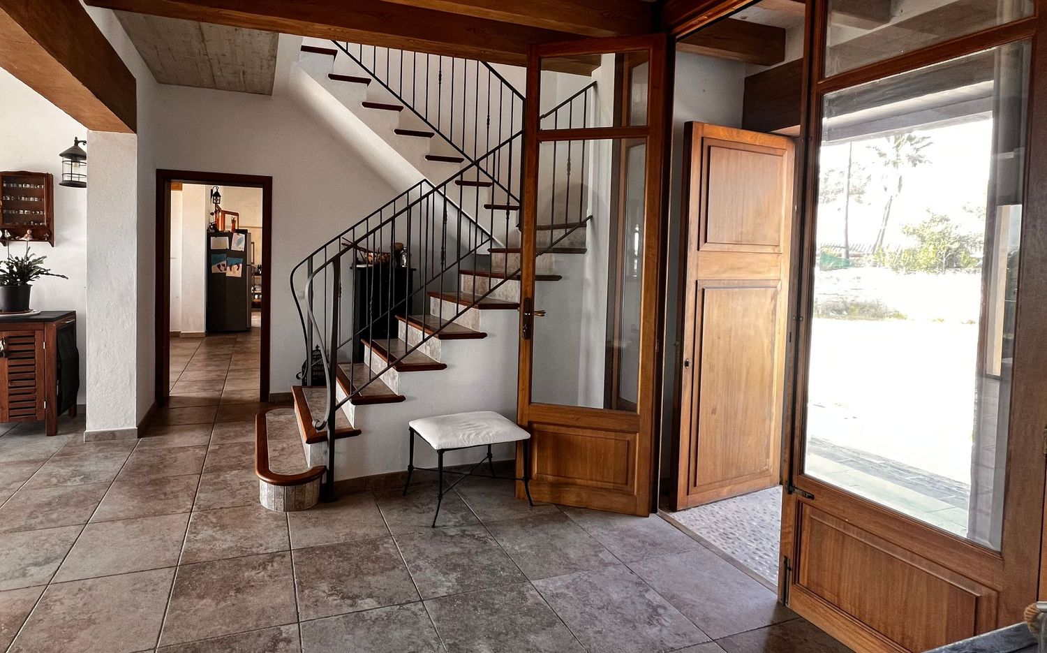 Elegant home entryway featuring a spiral staircase, tile flooring, wooden door, and abundant natural light.