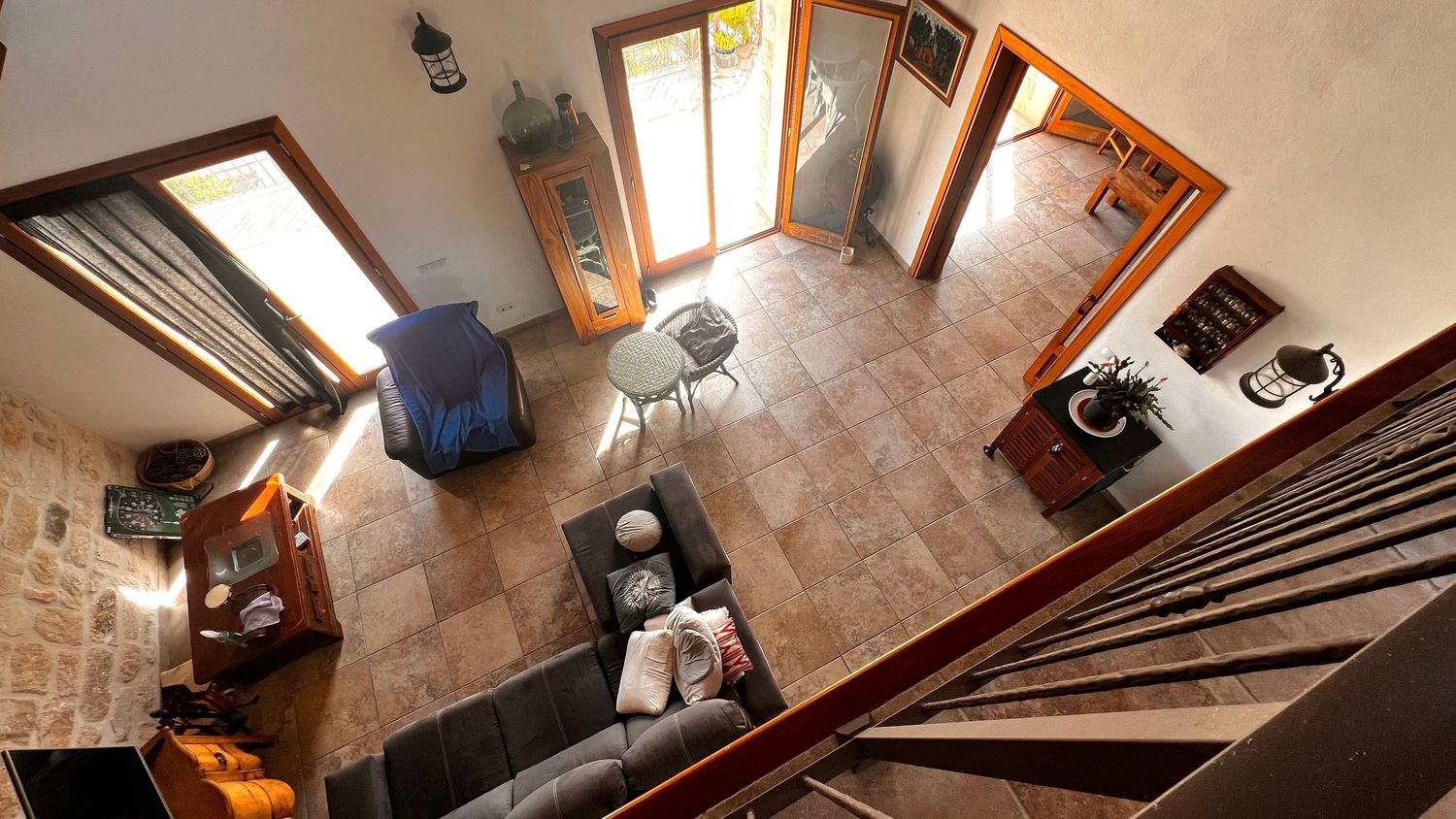 Aerial view of a rustic living room with tile floors, sofa, and natural wood doors.