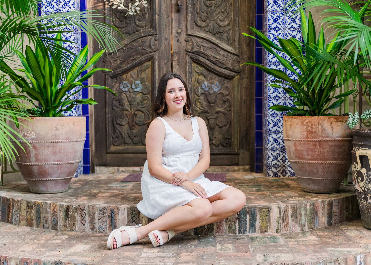 Girl sitting on decorative doorstep in front of Moroccan inspired wooden door at Jennifer's Gardens Inn in Austin, Texas