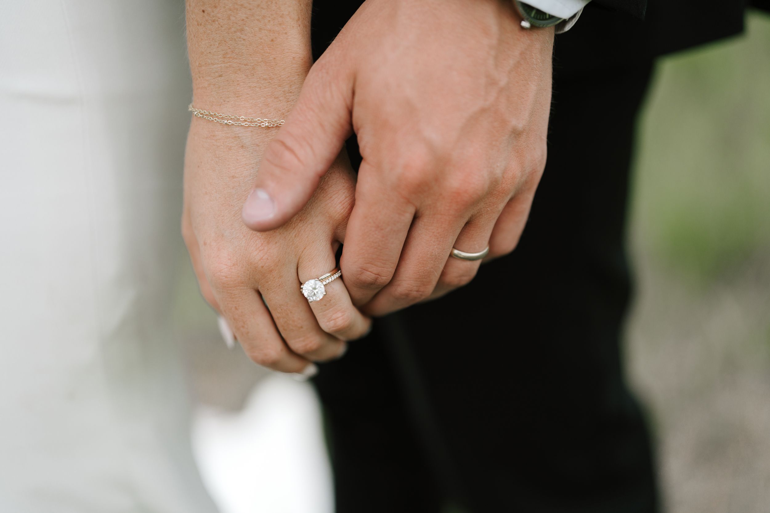 Close-up shot of newlyweds' hands with wedding rings intertwined.