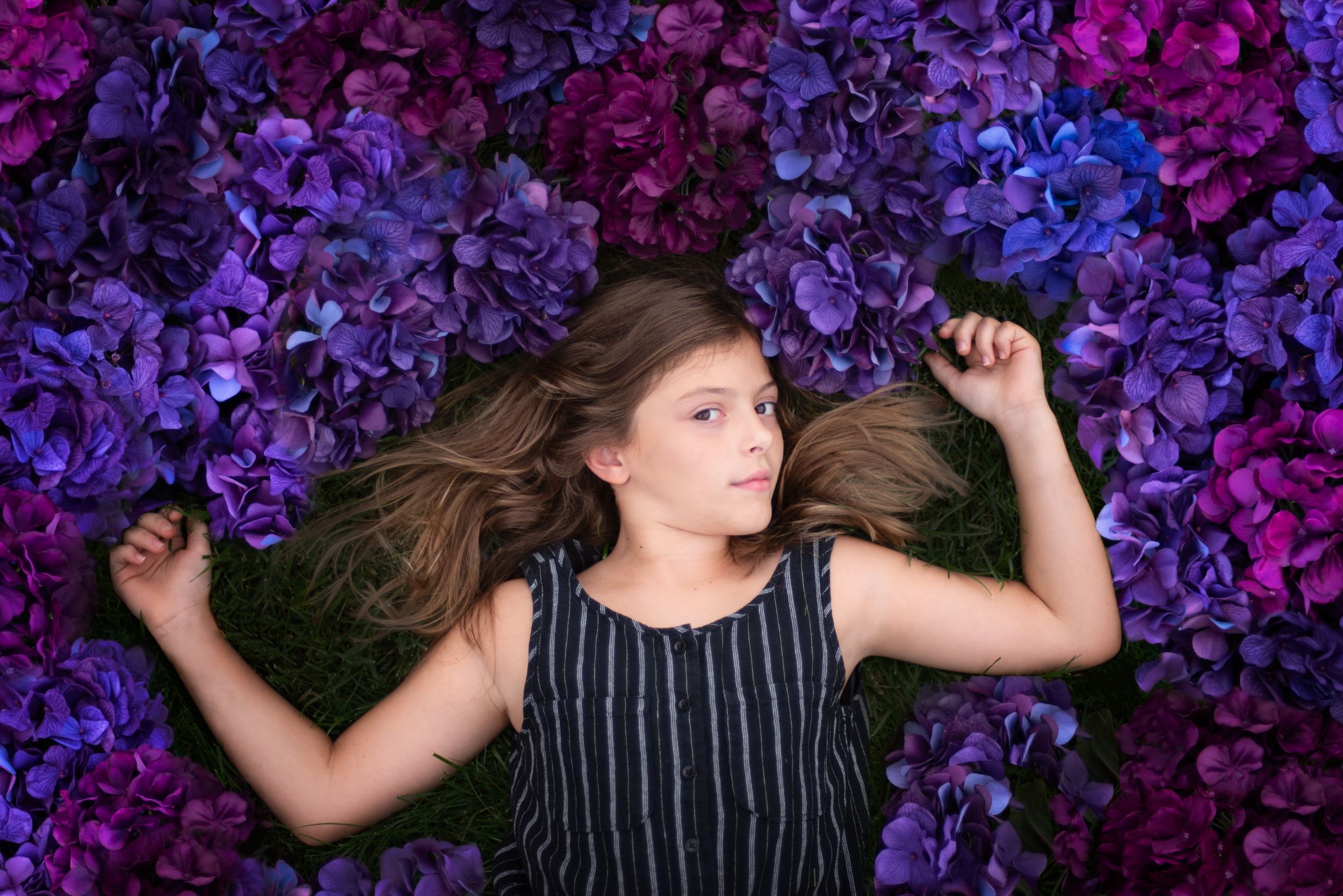 Portrait of child against vibrant purple and magenta hydrangea flowers.Middletown NJ