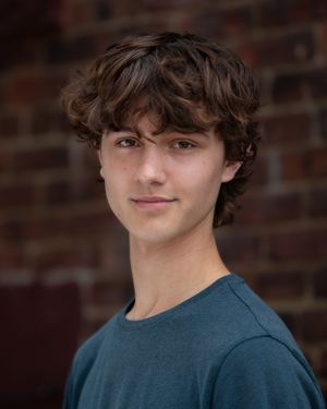 Headshot Portrait of young man in blue shirt against brick wall background in Atlantic Highlands NJ