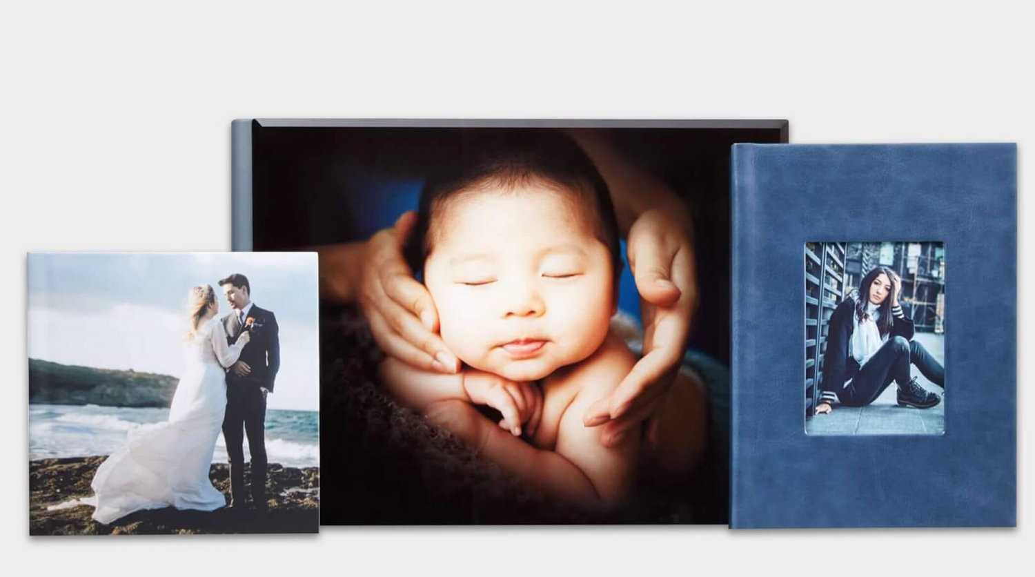 Three photo books featuring a wedding couple, sleeping newborn baby, and a family portrait in a blue linen album cover. Embracing Life’s Bea