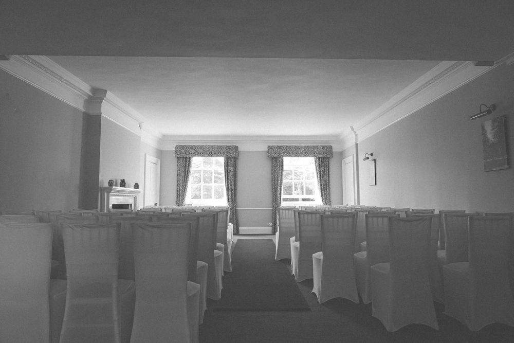 Empty wedding ceremony room with white chair covers and aisle runner.