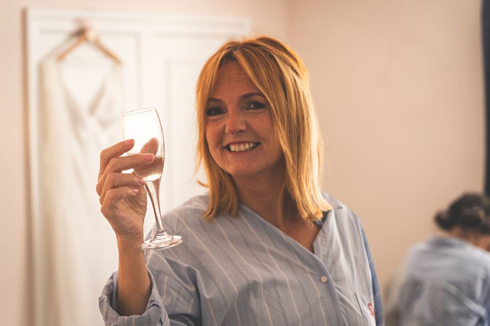 Person in striped shirt holding champagne glass and smiling in soft lighting.