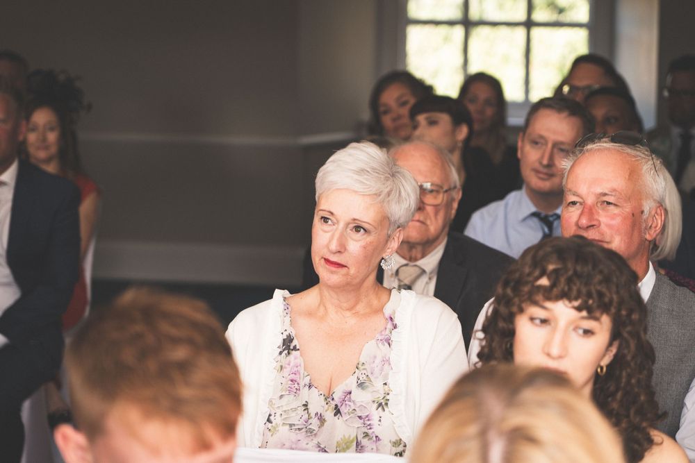 Wedding guests seated in rows watching ceremony with attentive expressions.