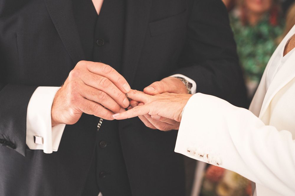 Close-up of hands exchanging wedding rings during ceremony.
