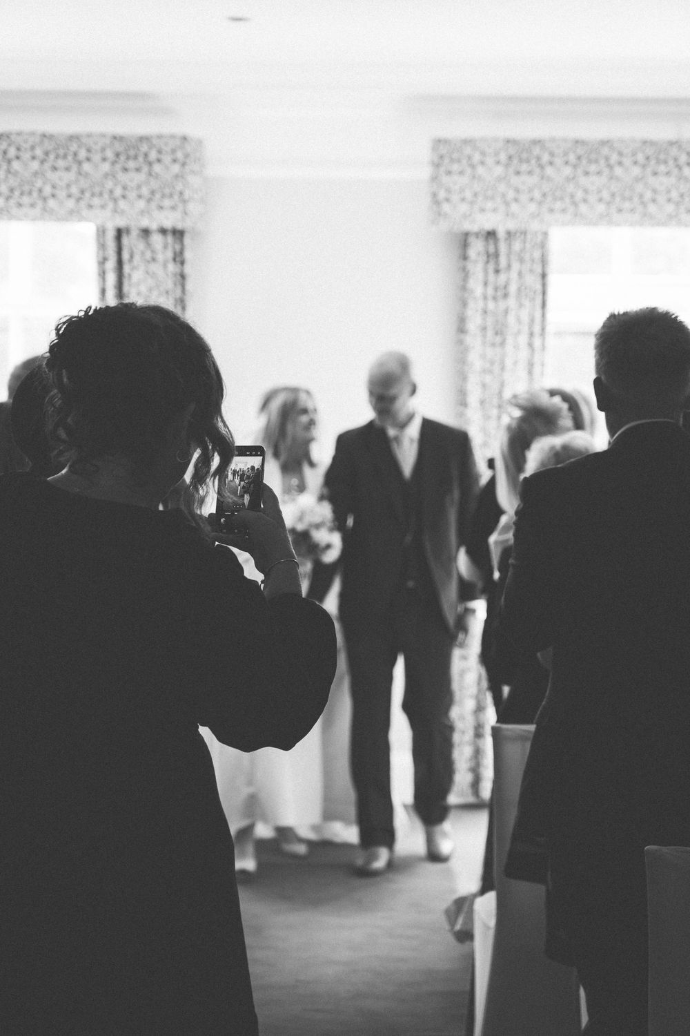 Wedding guests gather indoors at a reception venue during a celebration.
