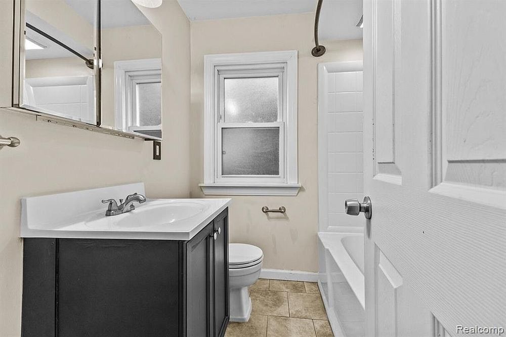Clean bathroom with dark vanity, white countertop, and tile flooring.