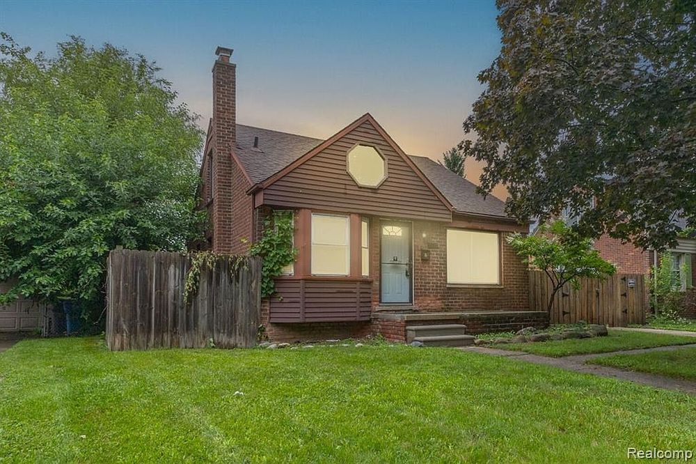 Charming brick bungalow with lush green lawn and mature trees at dusk.