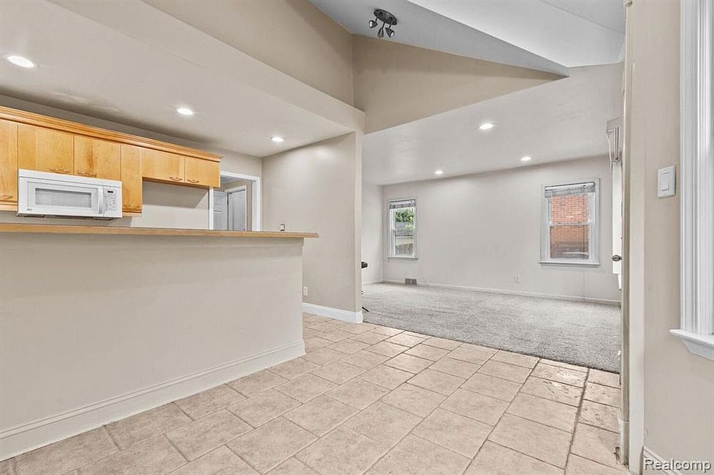 Open kitchen and living area with tile floors, light wood cabinets, and recessed lighting.