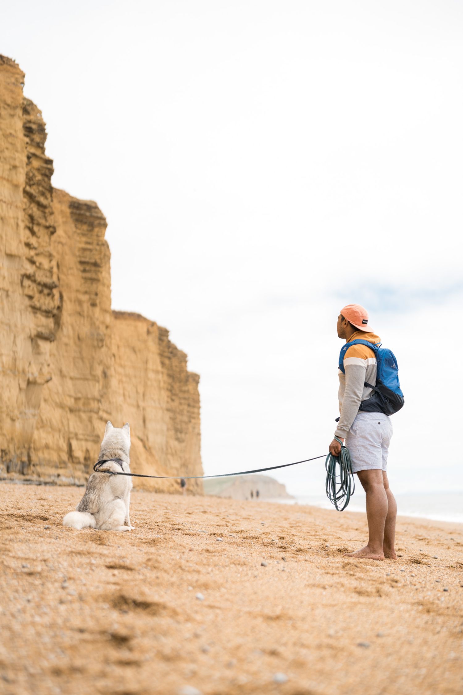 promeneur avec son chien devant les falaises ocres de west bay sur la jurassic coast en angleterre