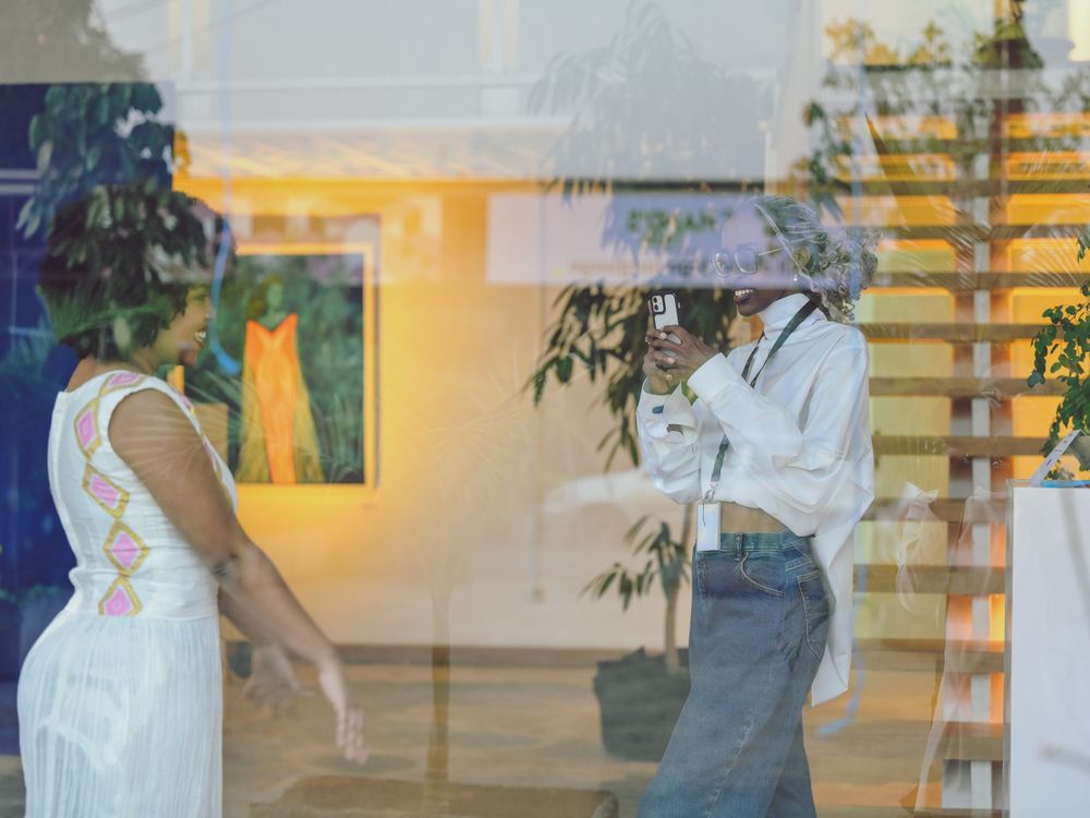 Art gallery exhibition space with paintings visible through reflective glass.