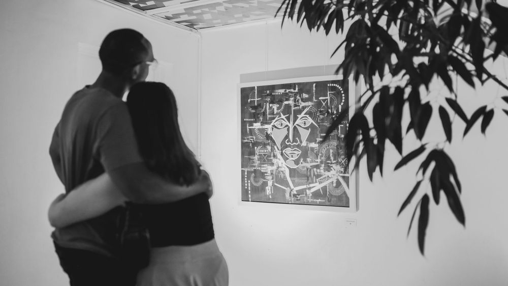 Black and white photo of two people viewing artwork in a gallery.