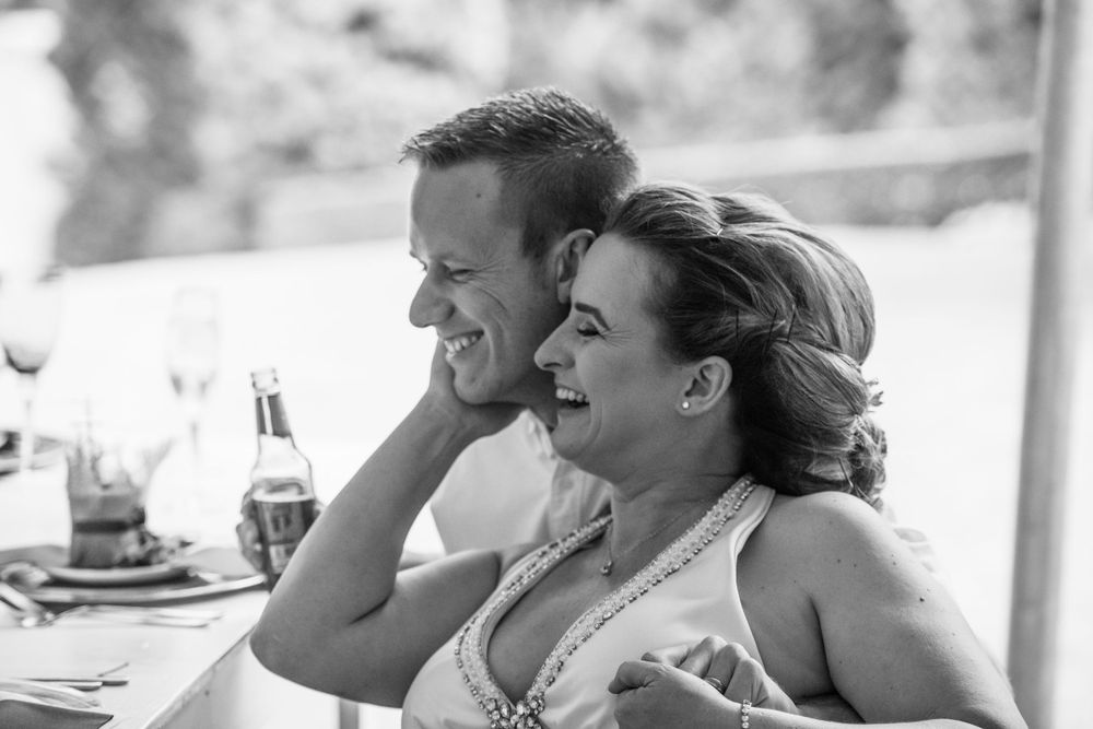 The bride and groom sharing a laugh at the speeches at their wedding, captured at  the wedding shoot