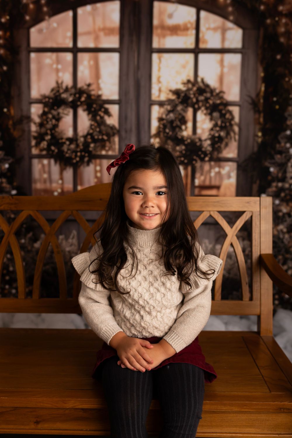 Warm holiday portrait with a cable knit sweater against a backdrop of Christmas wreaths.