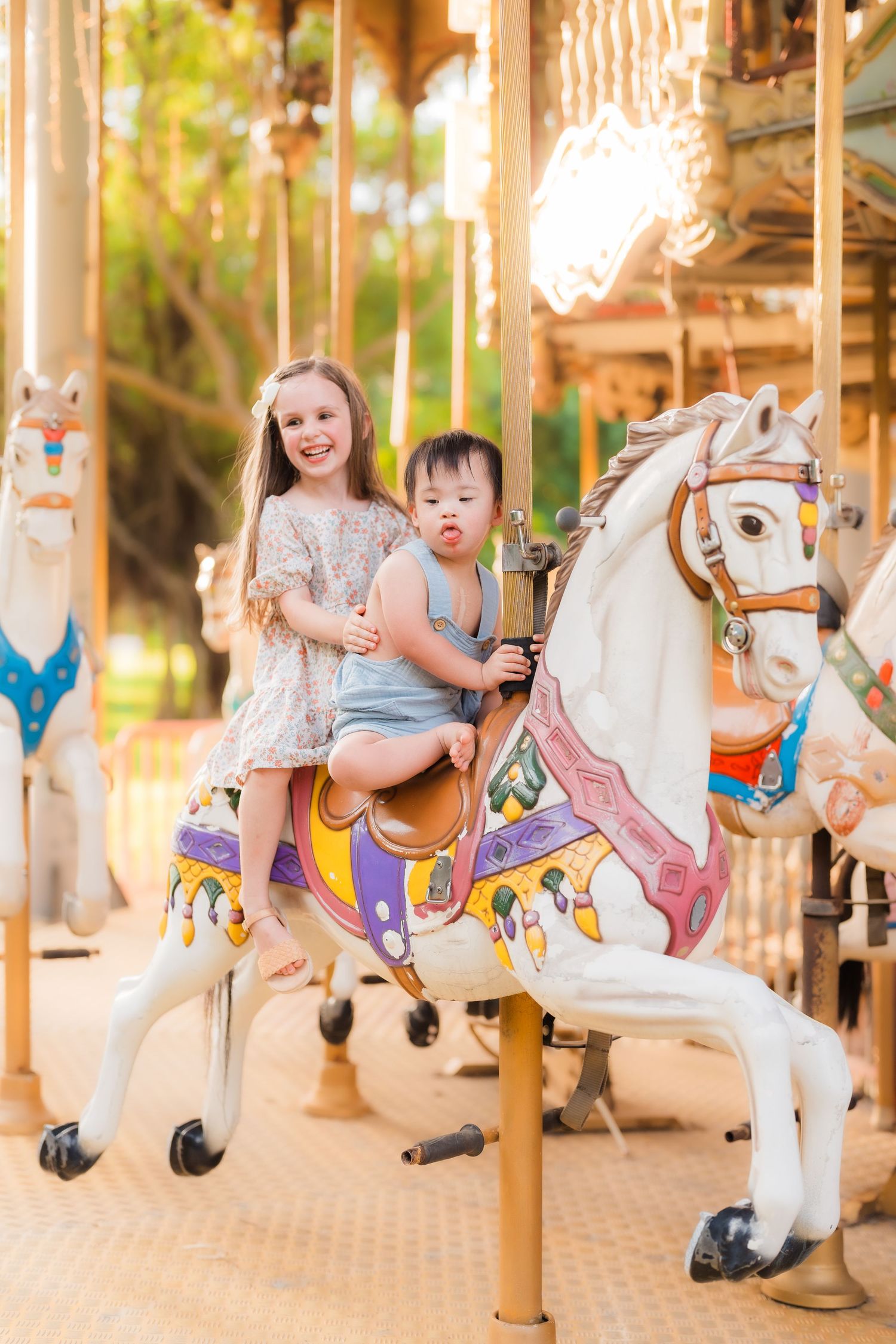 Two riders enjoying a vintage carousel with a decorated white horse.