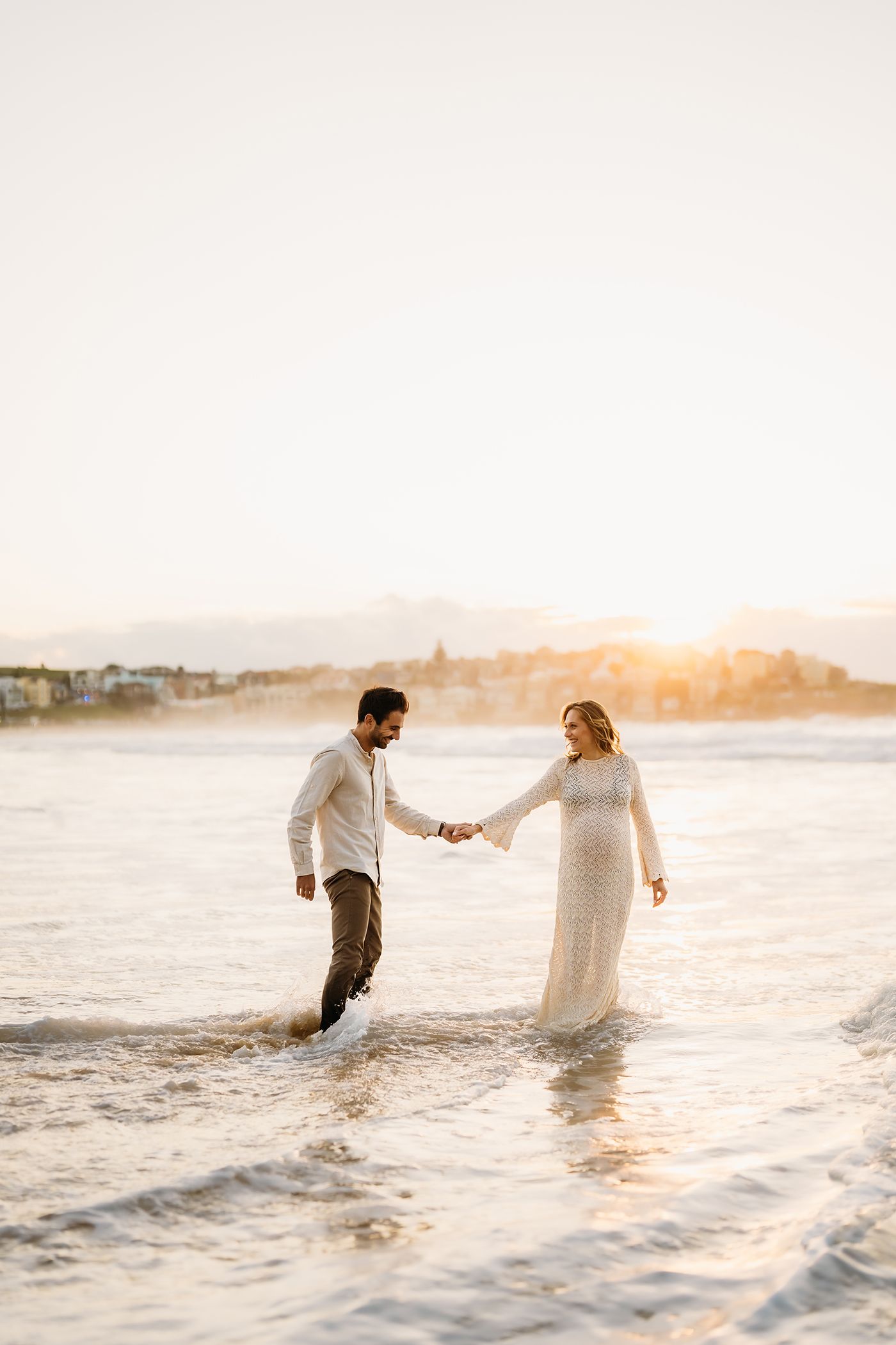Couple have fun in the ocean at Bondi Beach for their natural maternity session