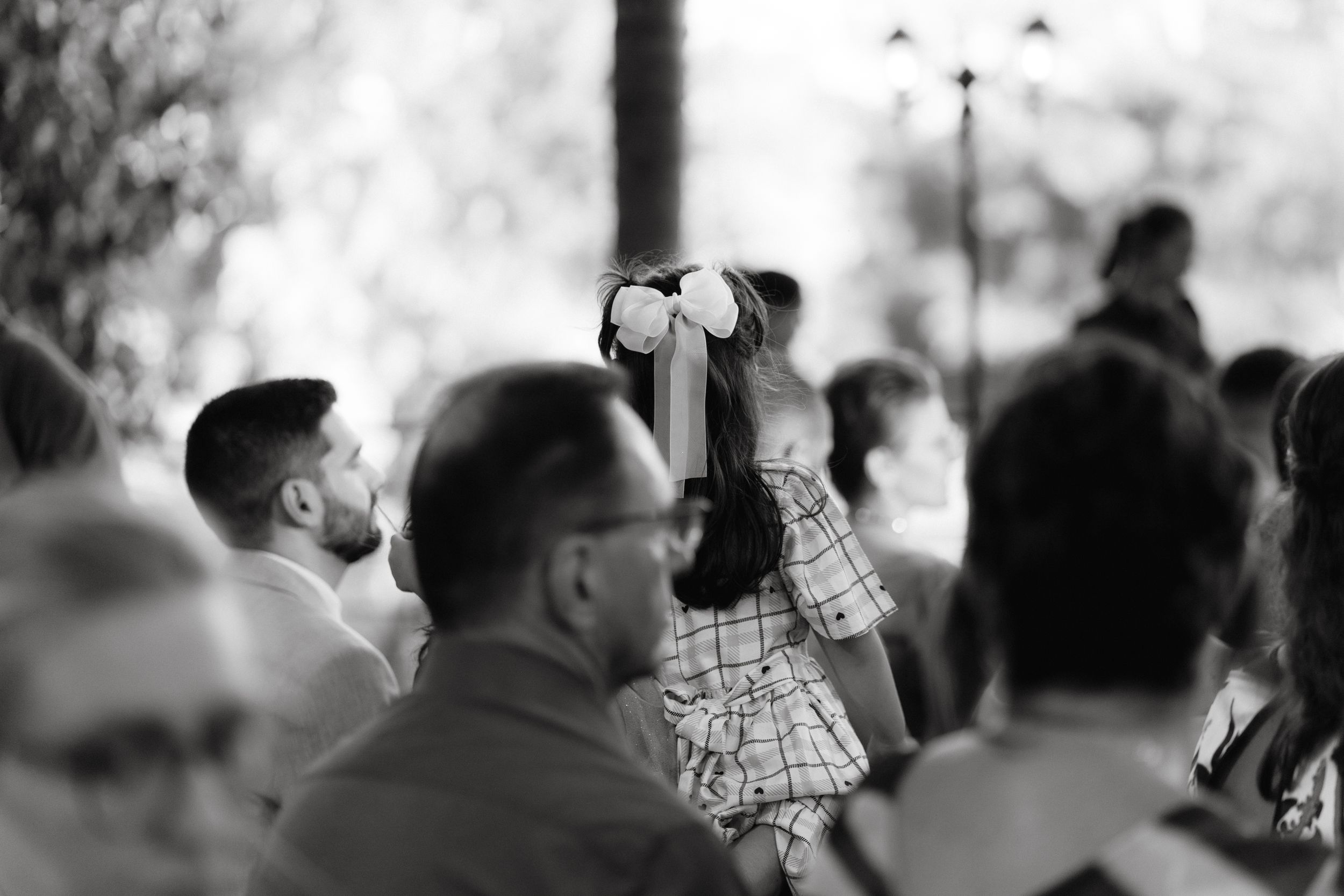 A crowd gathers at an outdoor event as someone raises a camera to capture a moment.