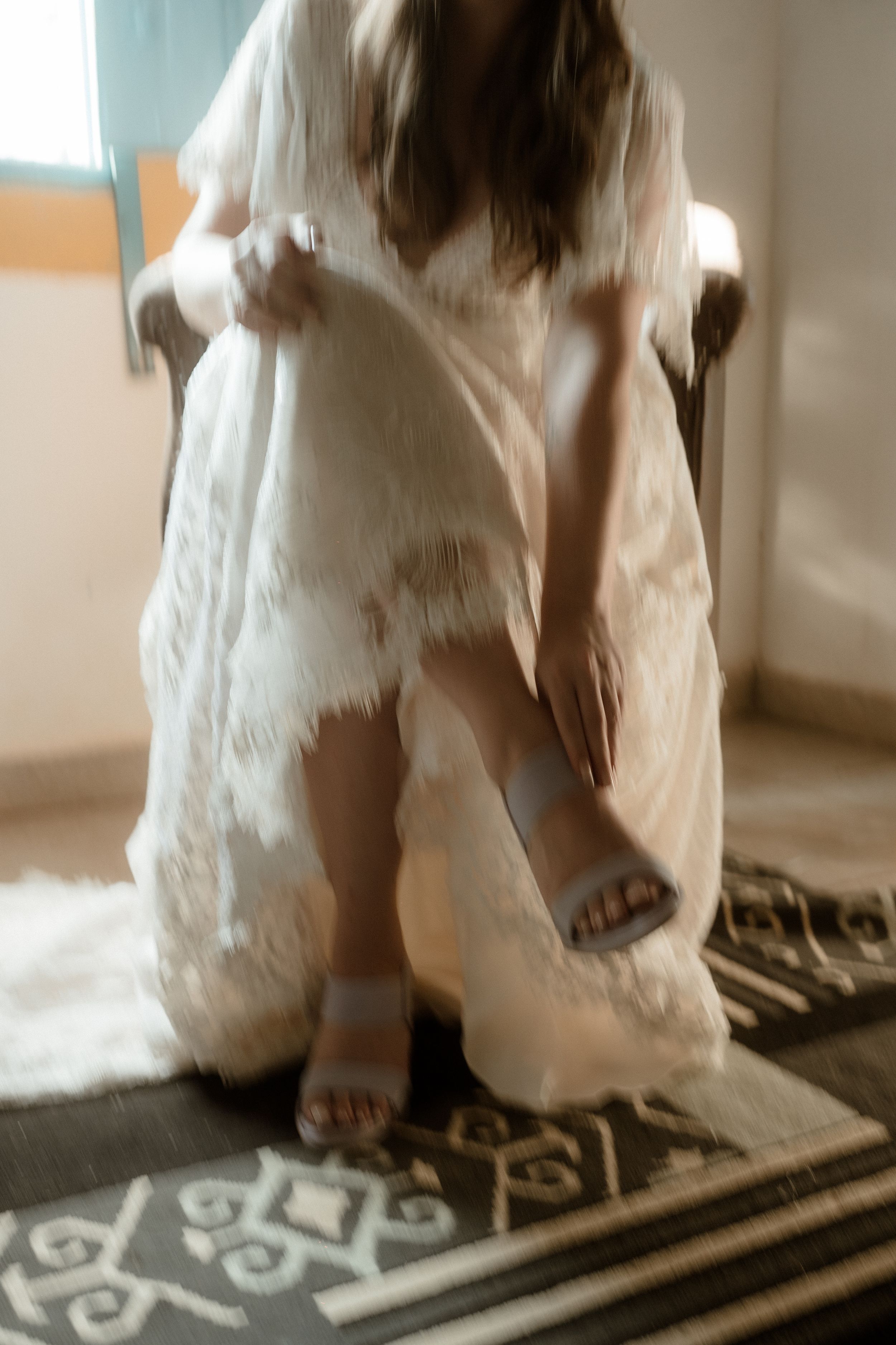 Wedding dress hem detail sweeping across patterned floor.
