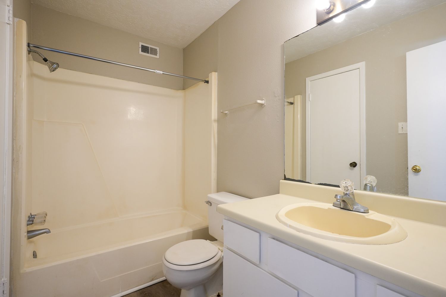Clean white bathroom with standard tub-shower combo, single vanity, and basic fixtures.
