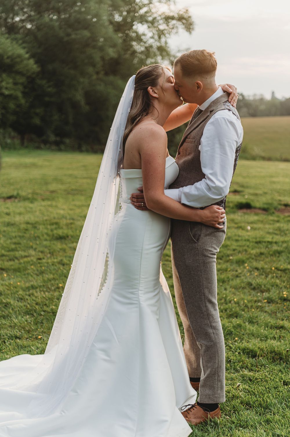 A romantic wedding moment captured in a sunlit meadow.