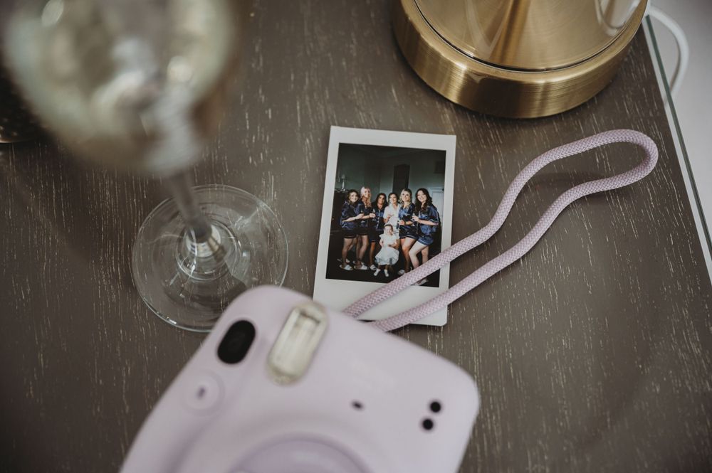 Polaroid photo and phone on wooden surface with wedding memories.