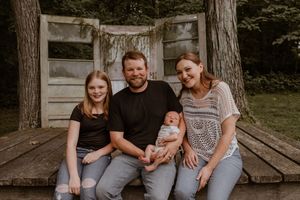 Family sitting together on rustic wooden platform outdoors.