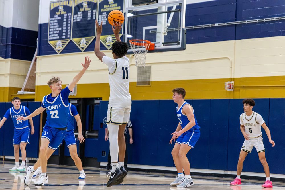 High school basketball player #11 leaps for a layup during an indoor game against players in blue uniforms.