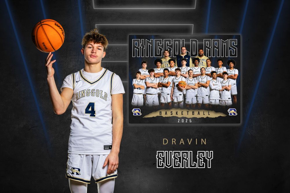High school basketball player in white jersey poses with basketball in front of dark backdrop for team photo shoot.
