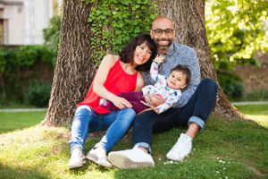 Papa et maman assis contre un tronc d'arbre, qui tiennent leur enfant dans leurs bras