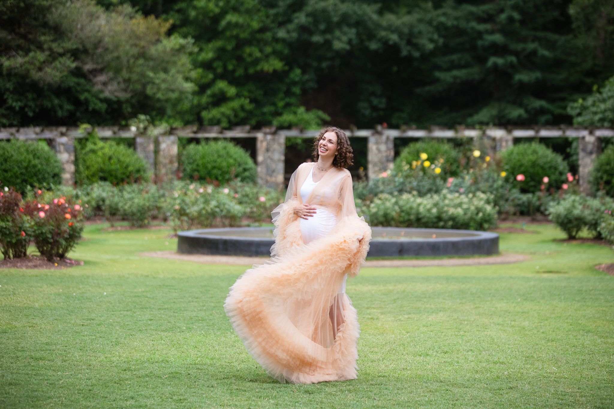 A person in a flowing peach dress twirls gracefully in a lush garden setting.