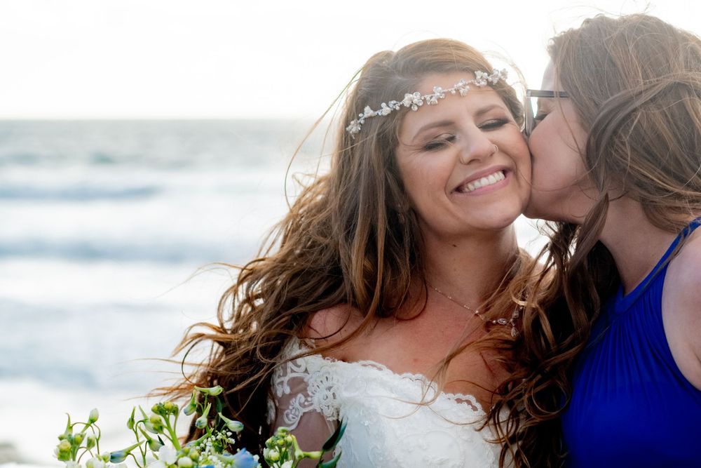 Happy wedding moment captured between family on a sunny beach, captured by a wedding photographer.