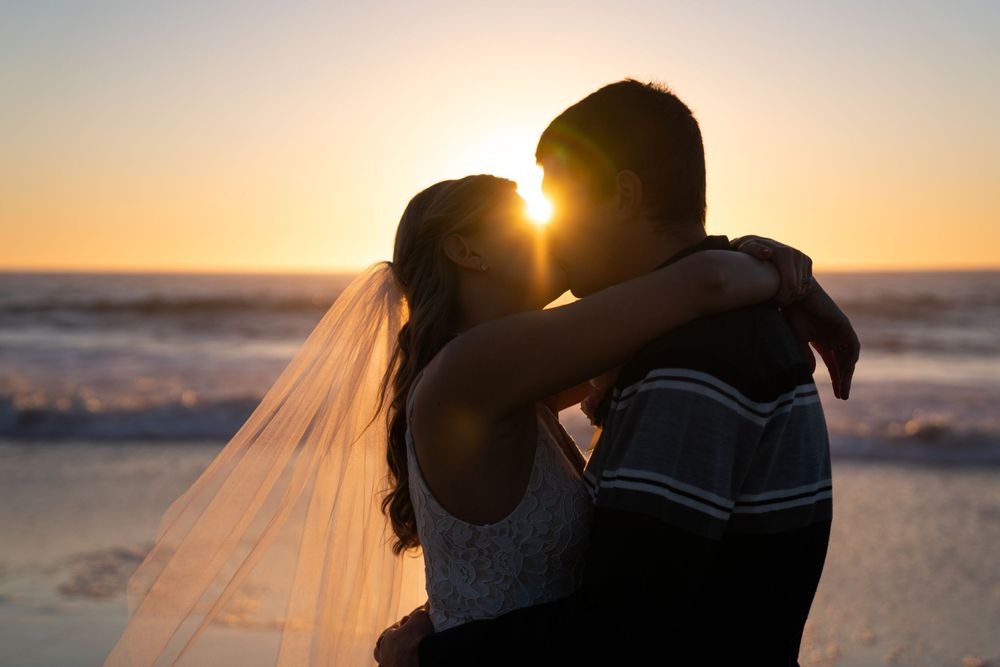 Romantic silhouette of newlyweds embracing during golden hour on the beach, captured by an elopement photographer.