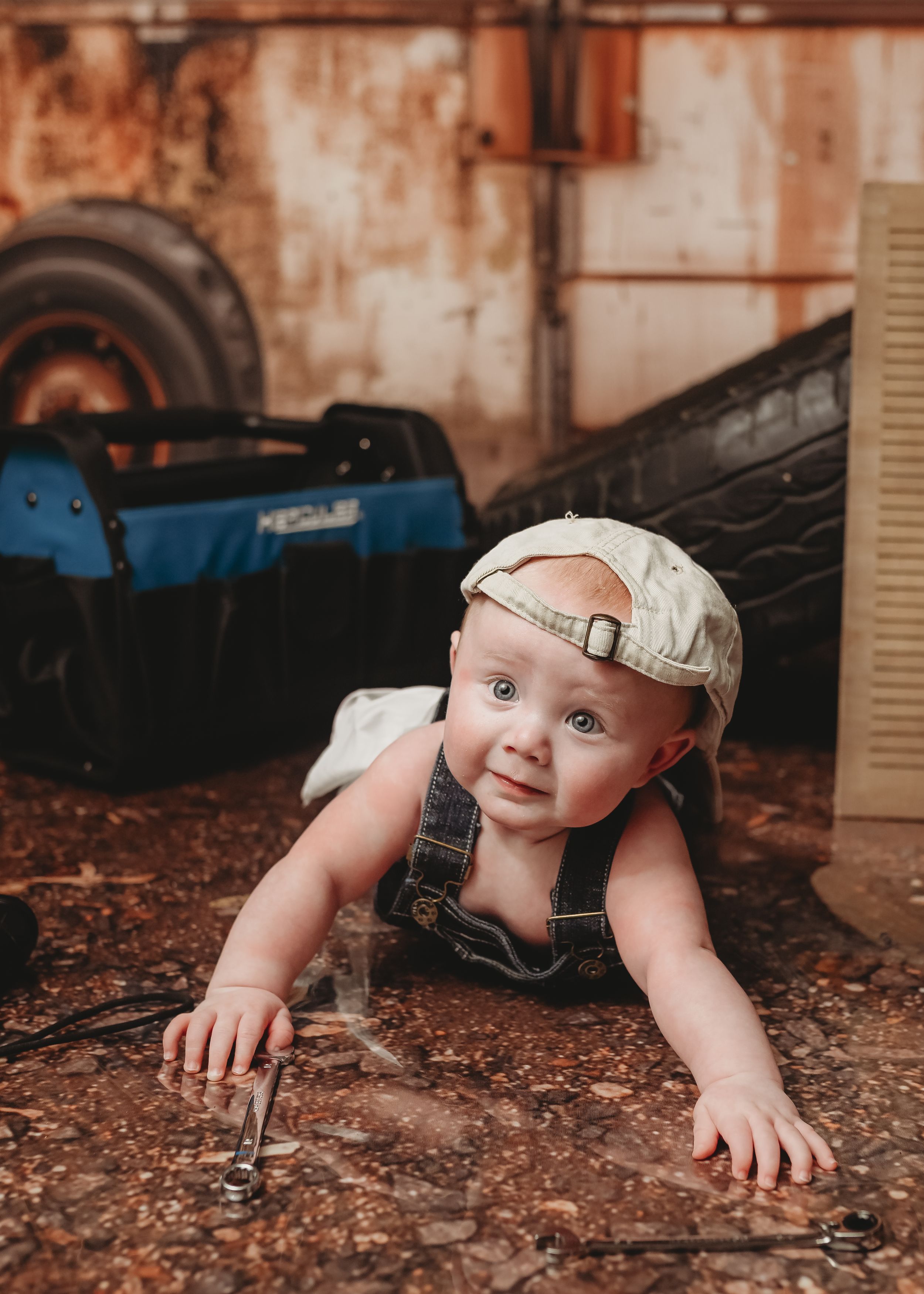 Baby crawling on rustic wooden floor in front of weathered wall.