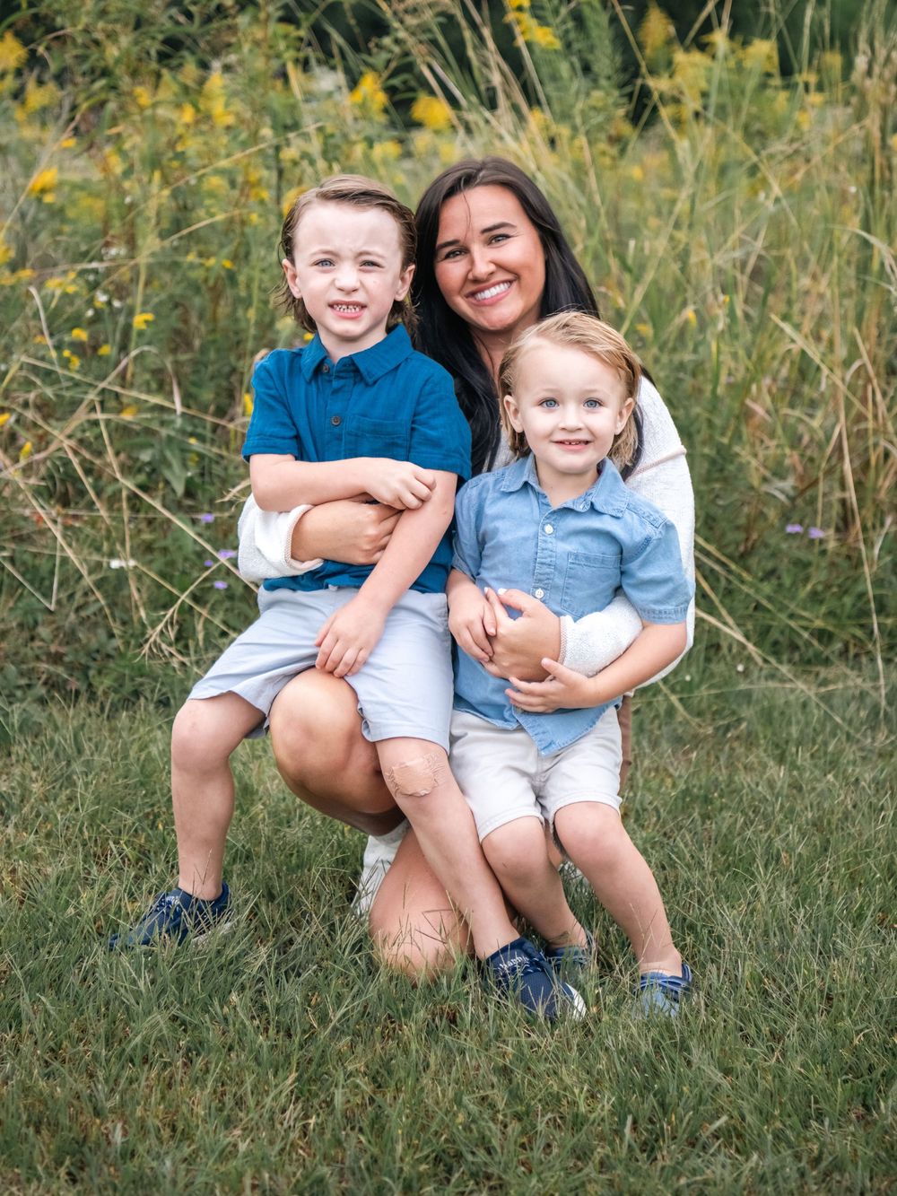 A playful outdoor family photoshoot in a field with yellow wildflowers during golden hour.