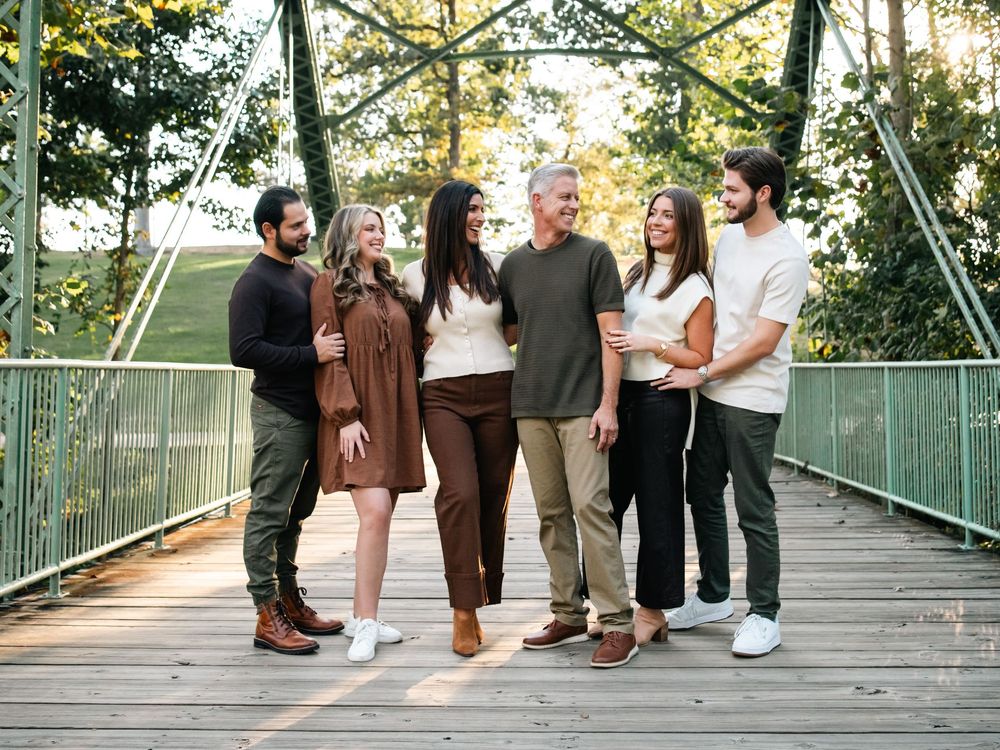 People walking and interacting on a wooden footbridge during an evening photoshoot.