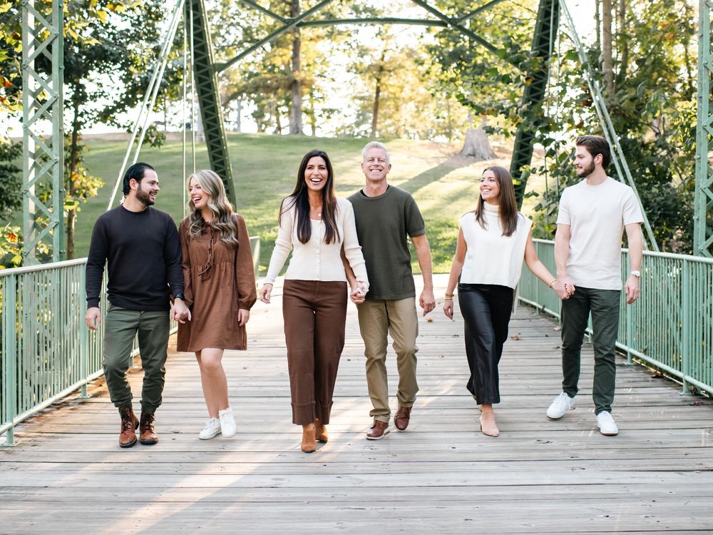 Multiple people strolling across a wooden bridge during golden hour photography session.