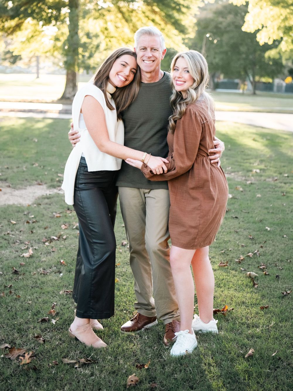 Relaxed outdoor family portraits captured in warm evening sunlight on grassy hill.